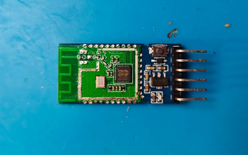 HC-05 Bluetooth Module Bluetooth electronic module with connection pins on a blue background.