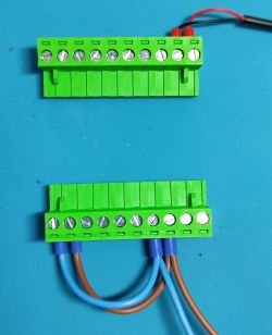 Green screw terminal blocks with brown and blue wires on a blue background