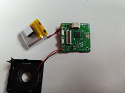 Internal parts of a small camera Disassembled components of a small camera: PCB, lithium-polymer battery, and lens.