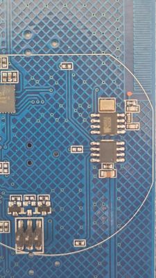 Close-up of a blue PCB with ICs, soldered components, and circuitry traces
