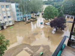 Powódź w mieście, woda zalewa ulice i częściowo budynki.