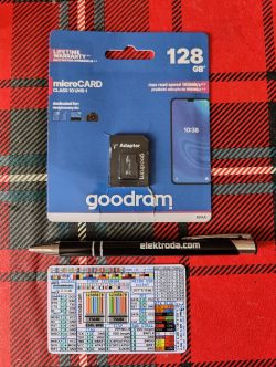 Goodram 128GB microSD card with adapter, pen with elektroda.com inscription, and a diagram card on a red plaid fabric background.