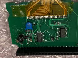 Close-up of a green printed circuit board with various electronic components, including a blue ceramic diode.