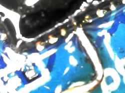 Close-up of a soldered wire on an integrated circuit on a blue PCB.