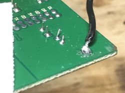 Close-up of PCB with black wire soldered to the edge GND pin