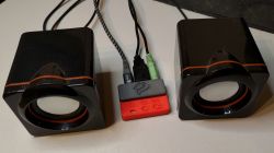 Small DIY audio player connected to two black speakers with red trim