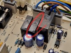 Zbliżenie na płytkę elektroniczną z zaznaczonym czerwonym kółkiem przekaźnikiem.
