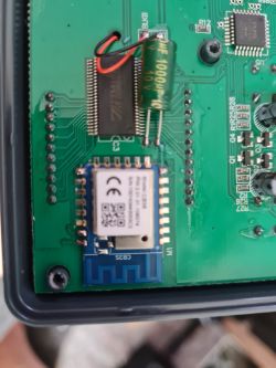 Close-up of a green printed circuit board with various electronic components and a chip.