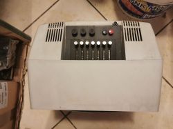 Panel sterowania starego instrumentu elektronicznego widziany z góry, z kilkoma pokrętłami i suwakami.