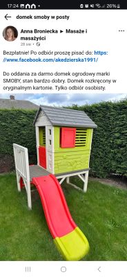 Domek ogrodowy SMOBY z kolorową zjeżdżalnią na trawniku Plastikowy domek ogrodowy SMOBY z czerwono-żółtą zjeżdżalnią na trawie