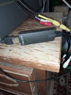 Zgrabny adapter USB Video DVR podłączony do kabli RCA na drewnianym biurku