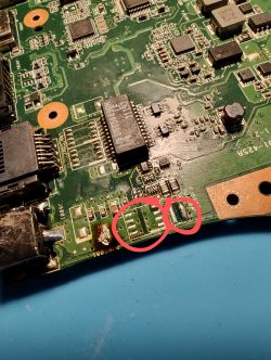 Zbliżenie na płytę główną laptopa Asus X53S z zaznaczonym miejscem w pobliżu gniazda zasilania.