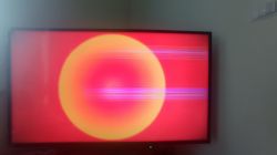Ekran telewizora z poziomymi paskami na tle czerwono-żółtym.