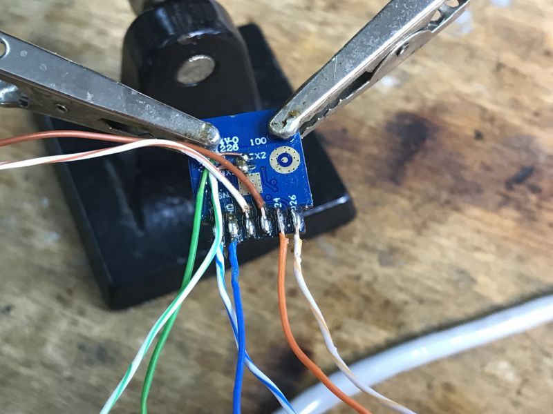 Soldering Ethernet Wires to Development Board Development board with attached Ethernet wires in a holder.