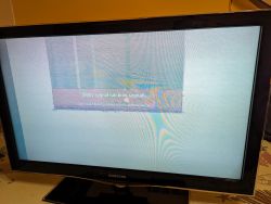 Telewizor Samsung z zielonym ekranem i paskami, pokazujący komunikat o słabym sygnale.