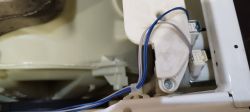 Zbliżenie na wnętrze pralko-suszarki Whirlpool z widocznymi przewodami i komponentami.