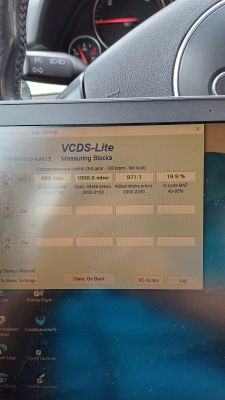 Ekran pokazujący parametry diagnostyczne w programie VCDS-Lite na tle deski rozdzielczej samochodu.