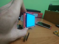 LCD display in red frame held at an angle, showing a blue background