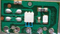 Zbliżenie na płytkę PCB z białym przyciskiem z zwartymi trzema pinami zaznaczonymi na niebiesko