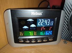 Stacja pogodowa Mebus z wyświetlaczem pokazującym temperaturę wewnętrzną i zewnętrzną oraz czas.