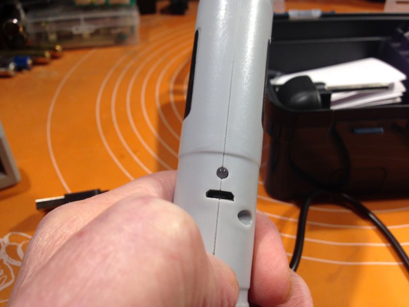 Zbliżenie na rękę trzymającą szary wkrętak elektryczny z widocznym przyciskiem.