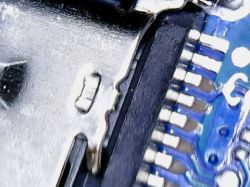 Zbliżenie uszkodzonego gniazda USB-C na niebieskiej płytce drukowanej