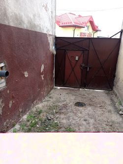 Wąskie podwórko z zamontowaną dwuskrzydłową bramą metalową między ścianami budynków.
