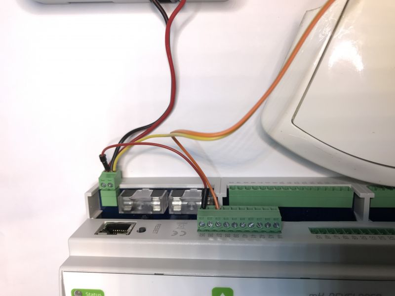 A section of a control panel or automation device with colored wires connected to screw terminals.