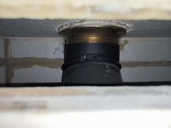 View of a fireplace interior with a black pipe and sealing.
