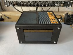 Black device with a front screen and STRUMYK text on the top surface.