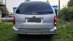 Tył Forda Windstara 1999 na trawie z zaświeconymi światłami tylnymi.