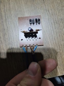 Układ elektroniczny z rozebranym zasilaczem do lampek choinkowych na drewnianym tle.