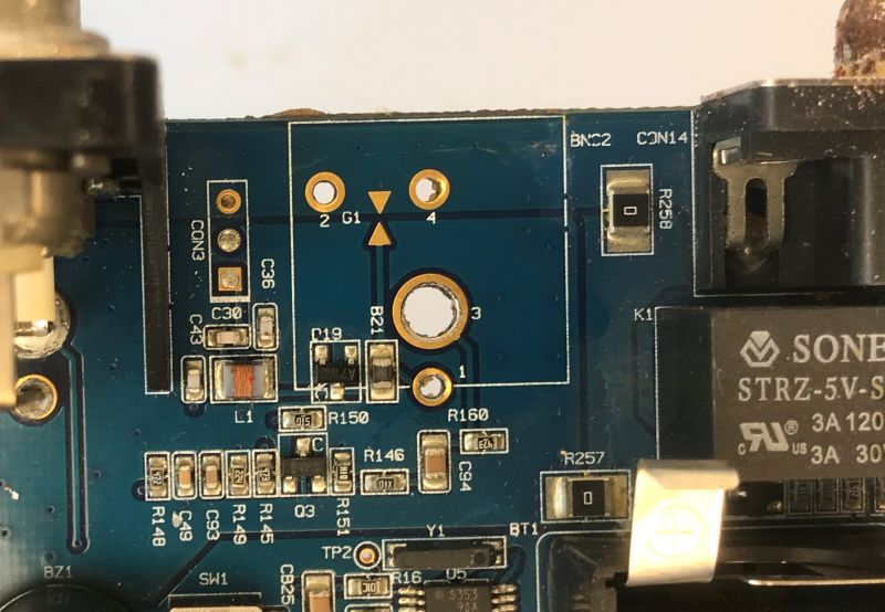 Close-up of a blue PCB with solder pads, traces, and printed component labels