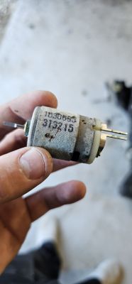Small electric motor held in hand with visible number 313215 on the casing.
