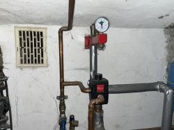 Instalacja grzewcza z zamontowanym zaworem i manometrem w piwnicy.