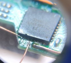 Close-up of a circuit board with thin copper wires attached.