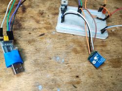 CB2S Board Connected to Breadboard Printed circuit board with relay connected to a breadboard on a table.