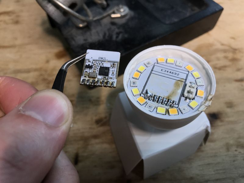 Electronic Circuit Board and LED Bulb Electronic circuit board in tweezers next to an LED bulb.