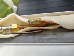 Zdjęcie rurek miedzianych z przejściówką, izolowanych materiałem.