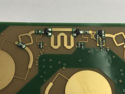 Close-up of a PCB with gold antenna traces and small SMD components