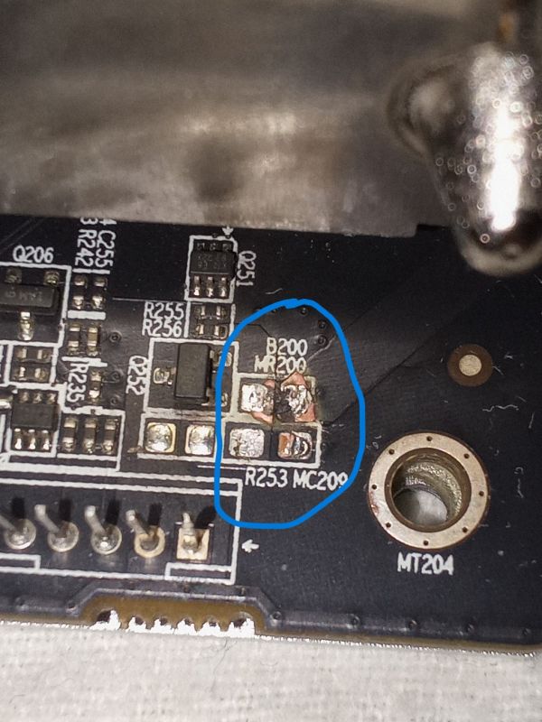 Zbliżenie na uszkodzony laminat karty graficznej Sapphire Radeon RX580 8GB z brakującymi dwoma elementami elektronicznymi zaznaczonymi na niebiesko.