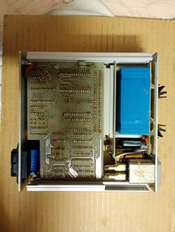Widok wnętrza urządzenia elektronicznego z odkrytą płytką PCB i komponentami