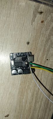 Moduł Bluetooth na płytce PCB z przylutowanymi przewodami, leżący na drewnianej powierzchni
