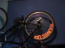 Spinning rear bicycle wheel with red LED dots forming a message on the rim