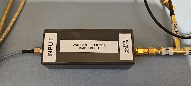 DAB+ Amplifier with Filter DAB+ amplifier with filter in a housing labeled with input and output signs.