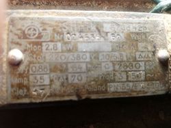 Tabliczka znamionowa silnika elektrycznego z widocznymi danymi technicznymi, częściowo nieczytelna z powodu zabrudzenia.