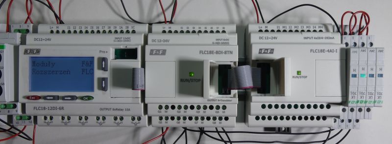 Programowalny sterownik logiczny z modułami rozszerzeń, podłączony przewodami.