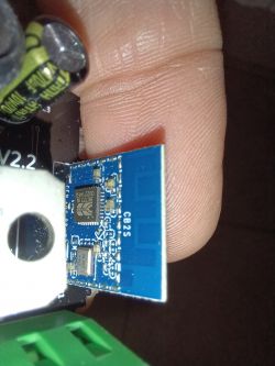 Close-up of an electronic module with components on a blue circuit board and nearby capacitors.