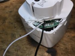 Close-up of a damaged white adapter showing wires and PCB.