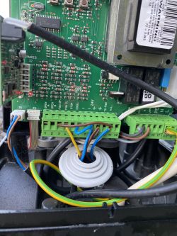 Close-up of electronic internals with wiring. Visible is a green circuit board with integrated circuits and colored wires connected to connectors.